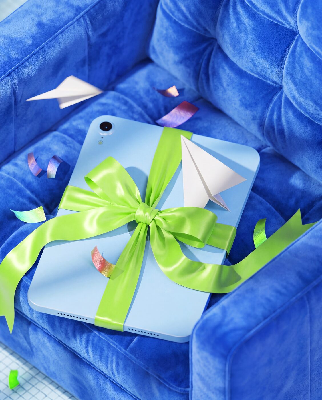 Gift-wrapped tablet with a green bow on a blue sofa